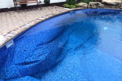 Vinyl pool liner lifted away from the wall in one large loose fold along the corner of the pool.