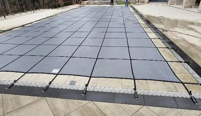 A fitted grey safety cover with webbing and deck anchors.