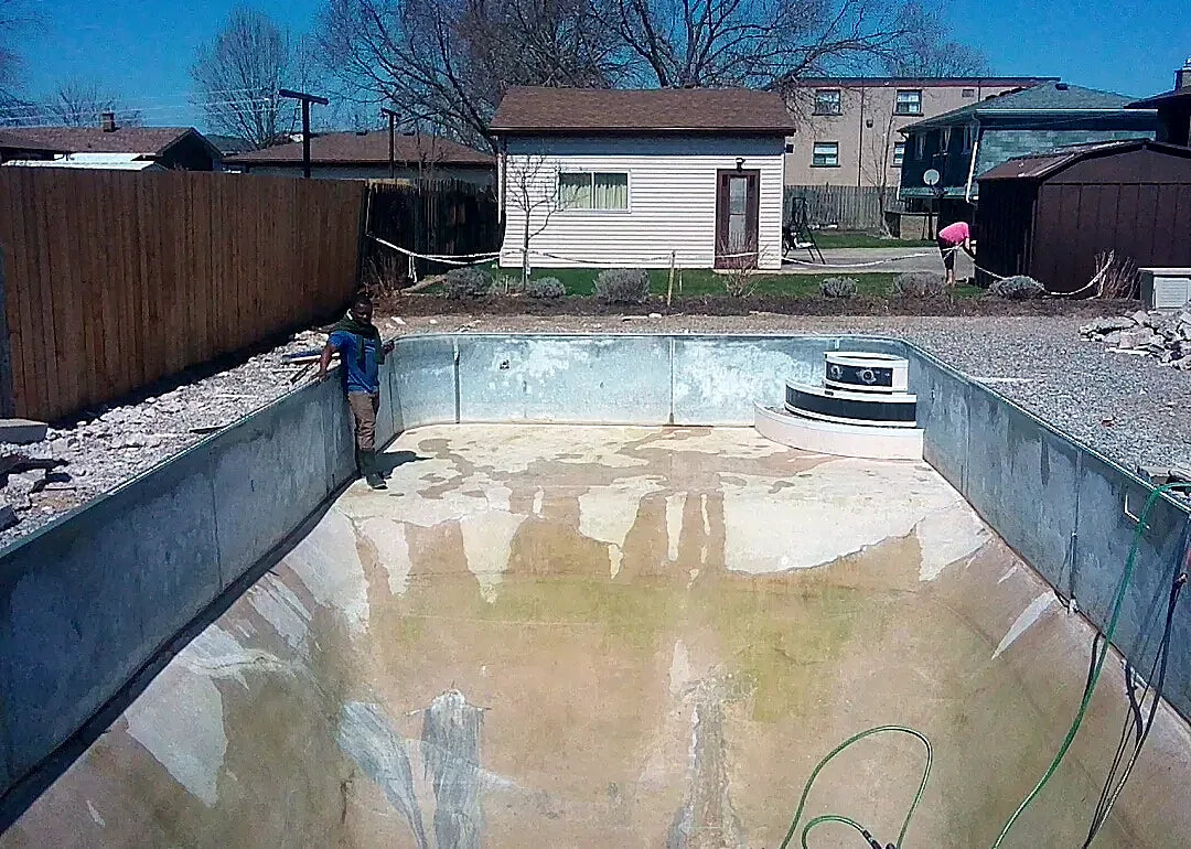 An older concrete pool, drained, with staining across the floor