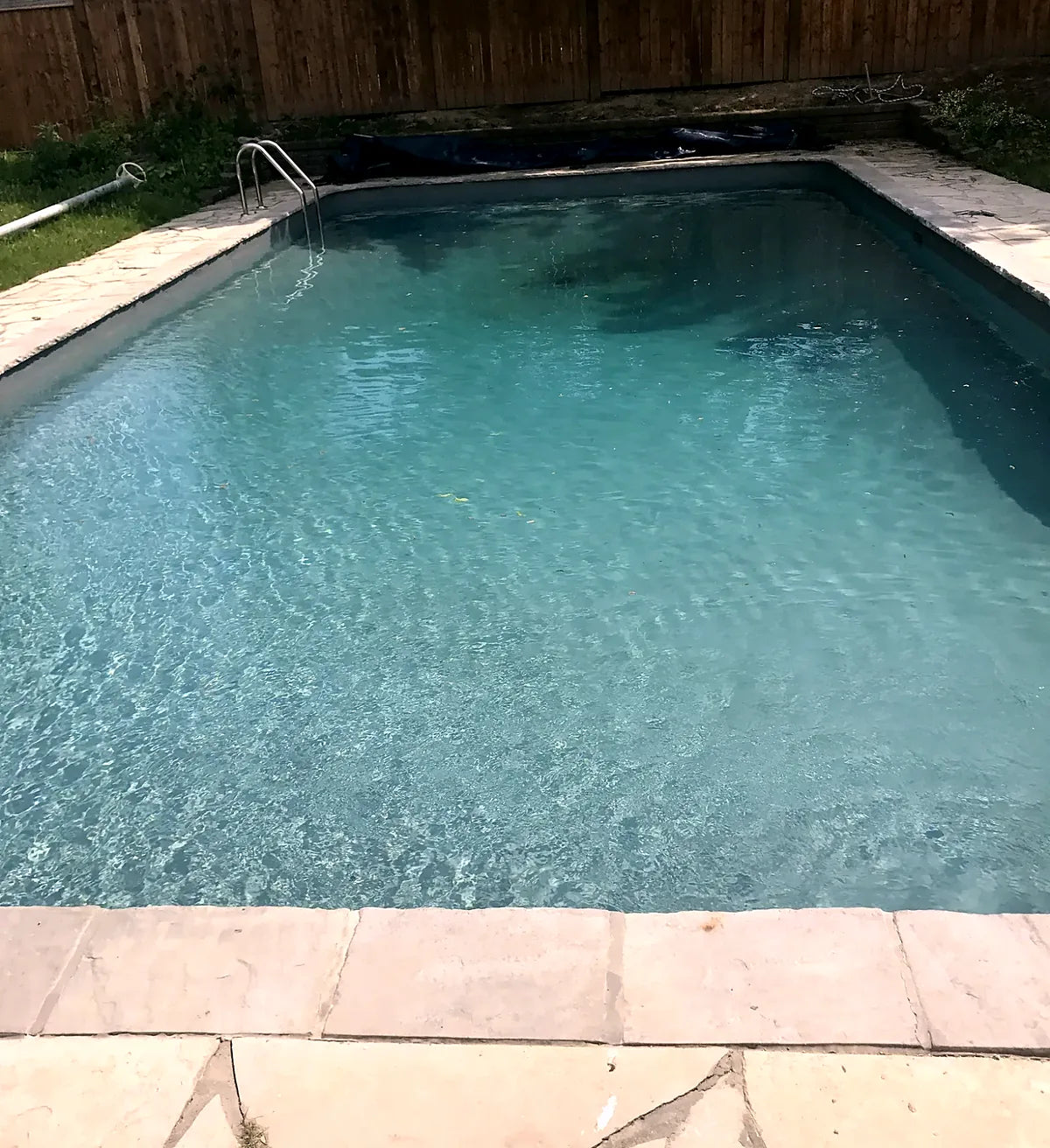 A rectangular pool filled with clear water, surrounded by flagstone