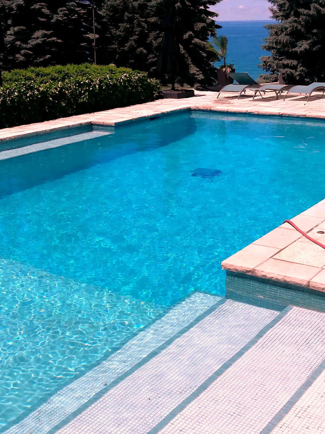 A finished painted pool with stone coping and lounge chairs