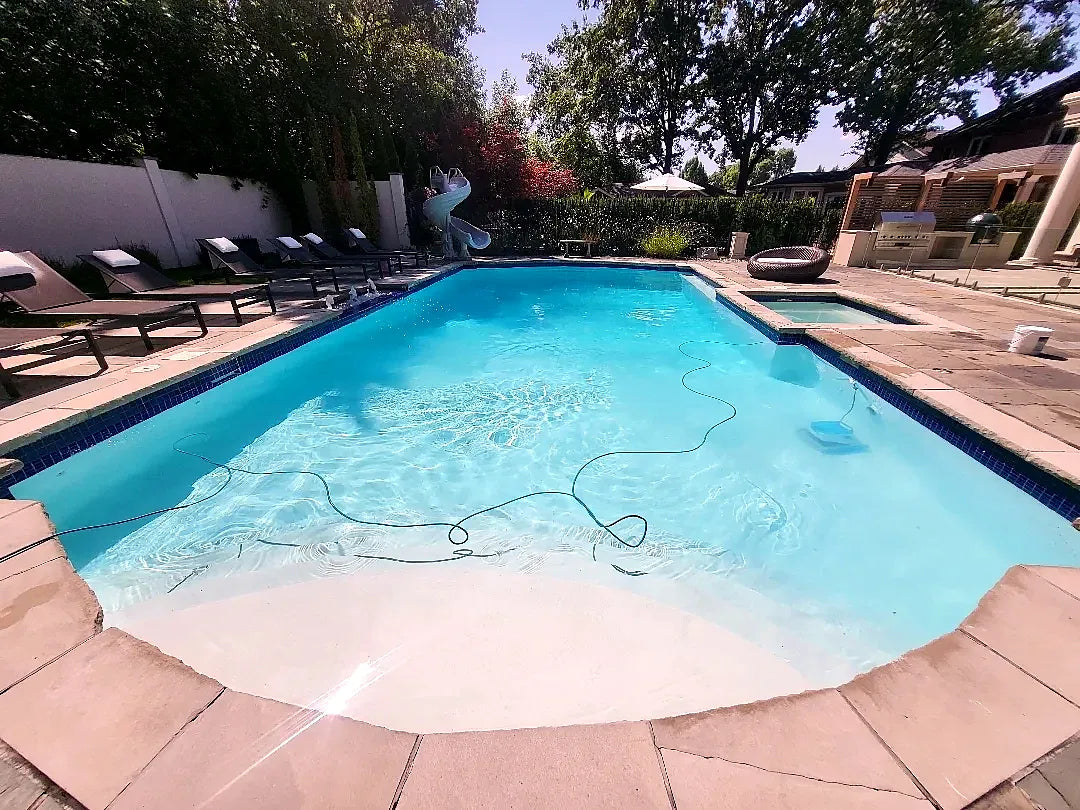 After: the pool refilled with clear water and new dark blue waterline tile