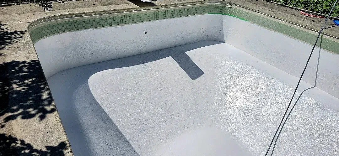 White finish being applied inside the pool, with green mosaic waterline tile