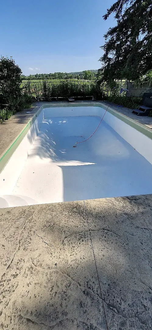 The white refinished pool seen from the shallow end