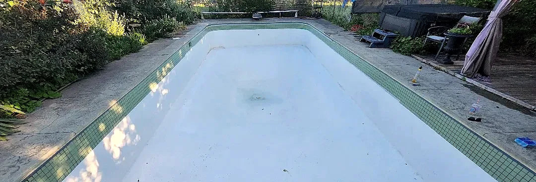 The refinished white pool with its green mosaic waterline