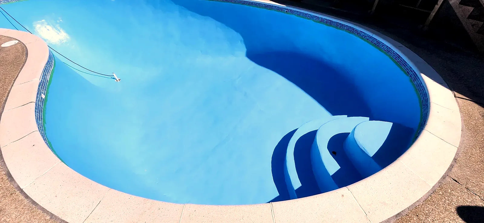 After: the same pool painted bright blue, with curved entry steps and a mosaic waterline